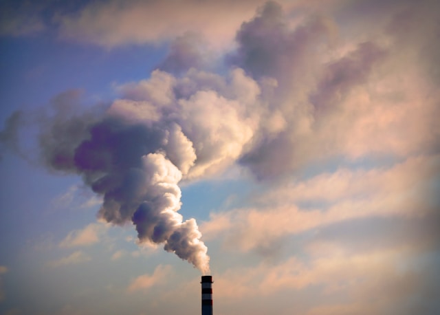 A smokestack blowing a gray cloud into the air